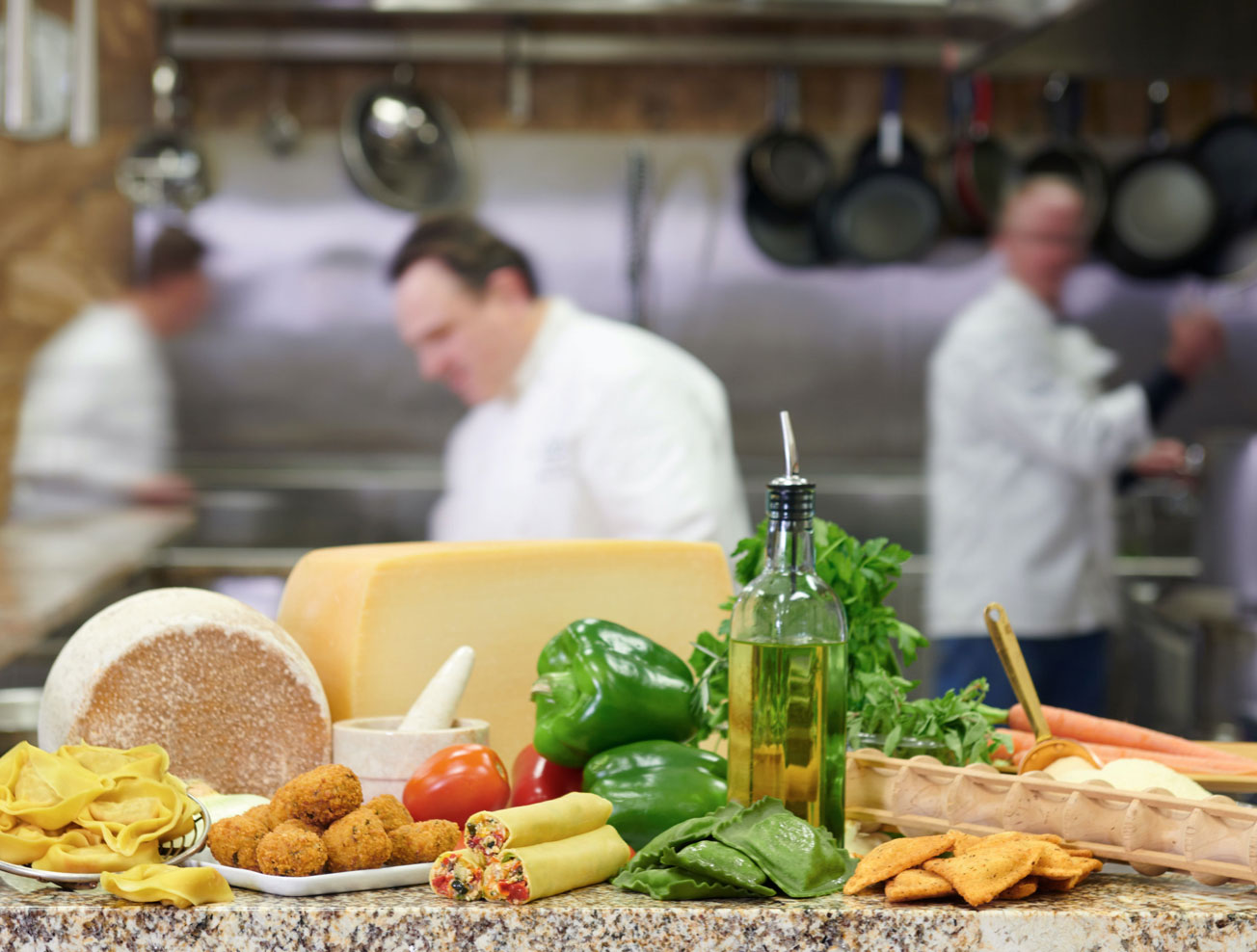 Ingredients displayed on a table with chefs cooking in the background
